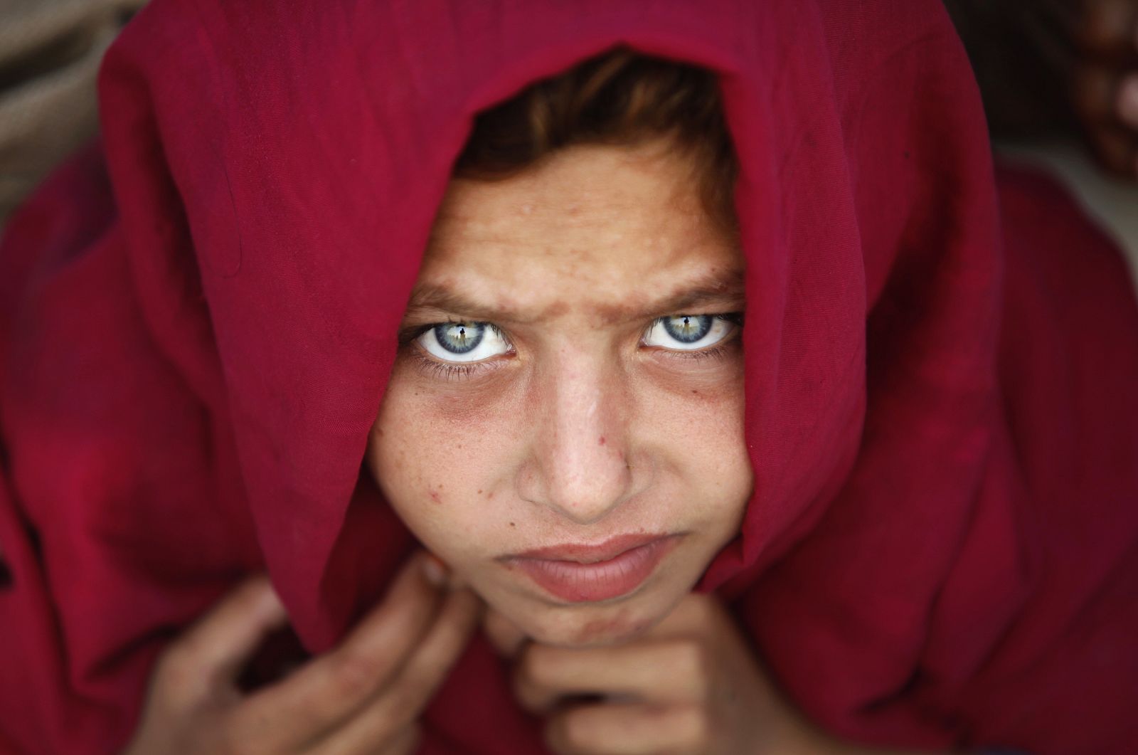 Kalsoom, 6, who was fleeing a military offensive in South Waziristan, sits in a queue with others to receive food handouts at a distribution point for IDPs in Dera Ismail Khan