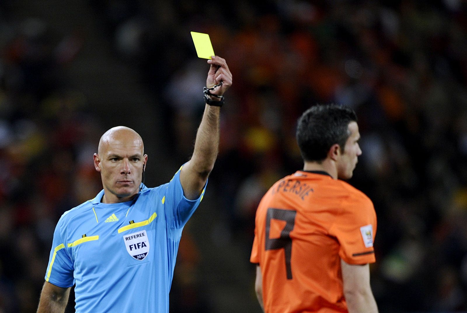 Referee Howard Webb of England shows the yellow card to Netherlands' Robin van Persie in Johannesburg