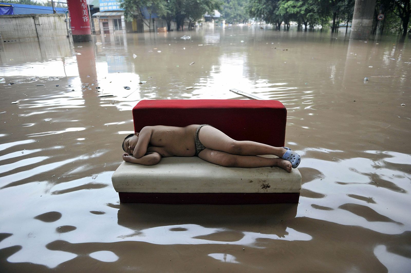 A child sleeps on a couch on a flooded street in Chongqing municipality