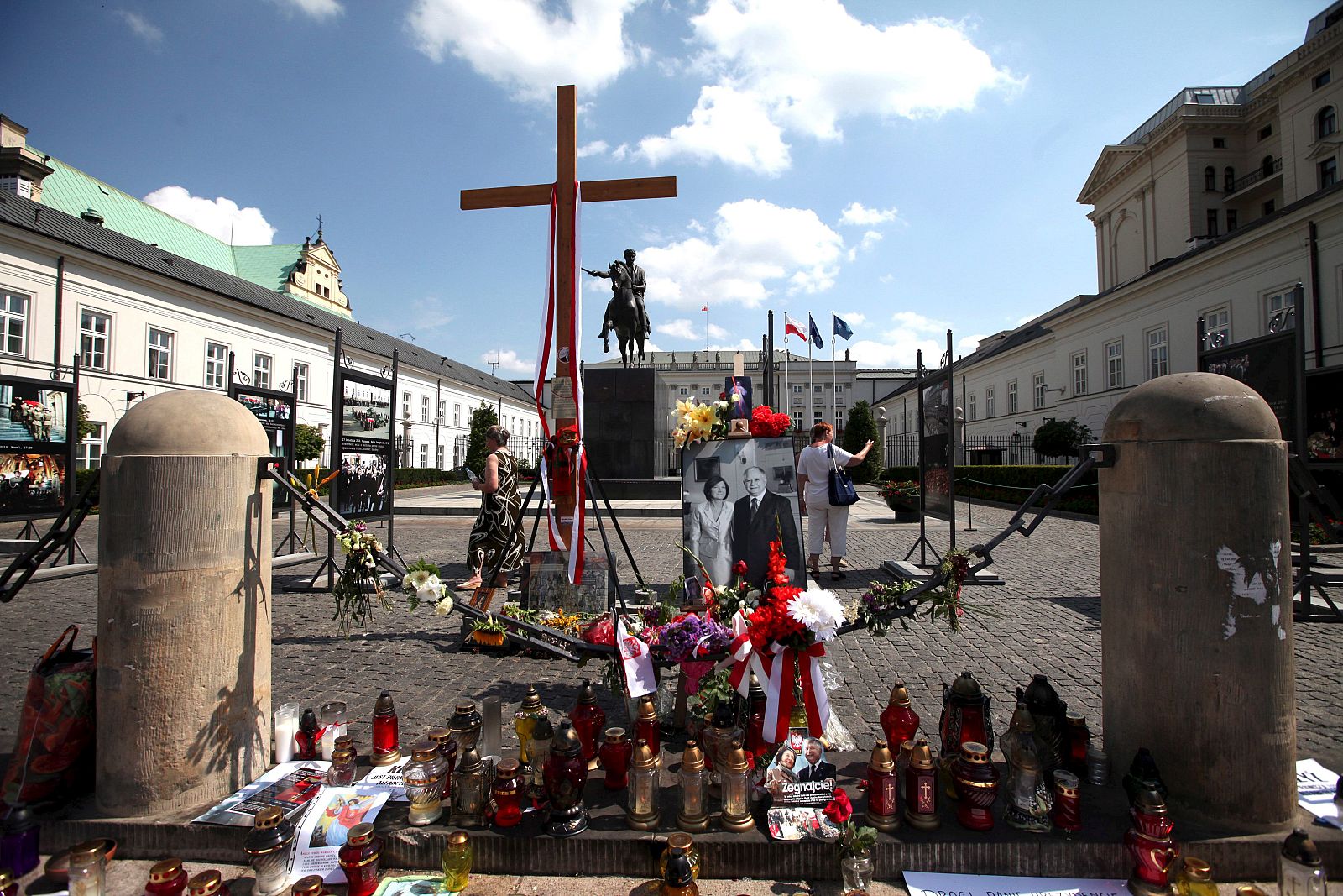 La población polaca continúa llevando flores y velas junto a una cruz de madera del Palacio presidencial.