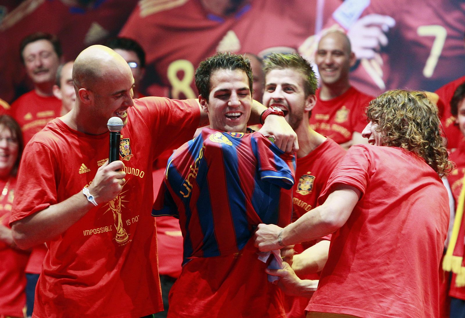 Spain's Pepe Reina and Carles Puyol put a Barcelona shirt on team-mate Cesc Fabregas as they celebrate their victory in Madrid