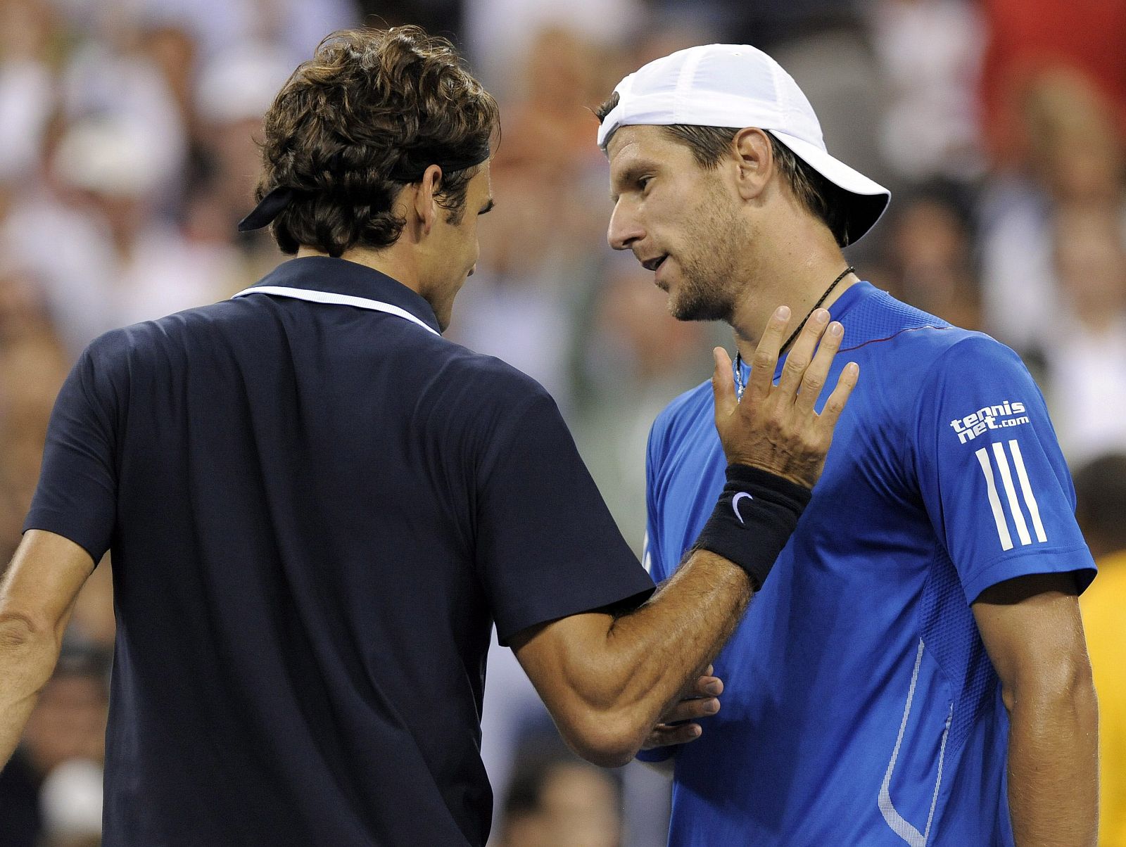 El suizo Roger Federer habla con el austríaco Jurgen Melzer tras  ganarle en el Flushing Meadows del US Open.