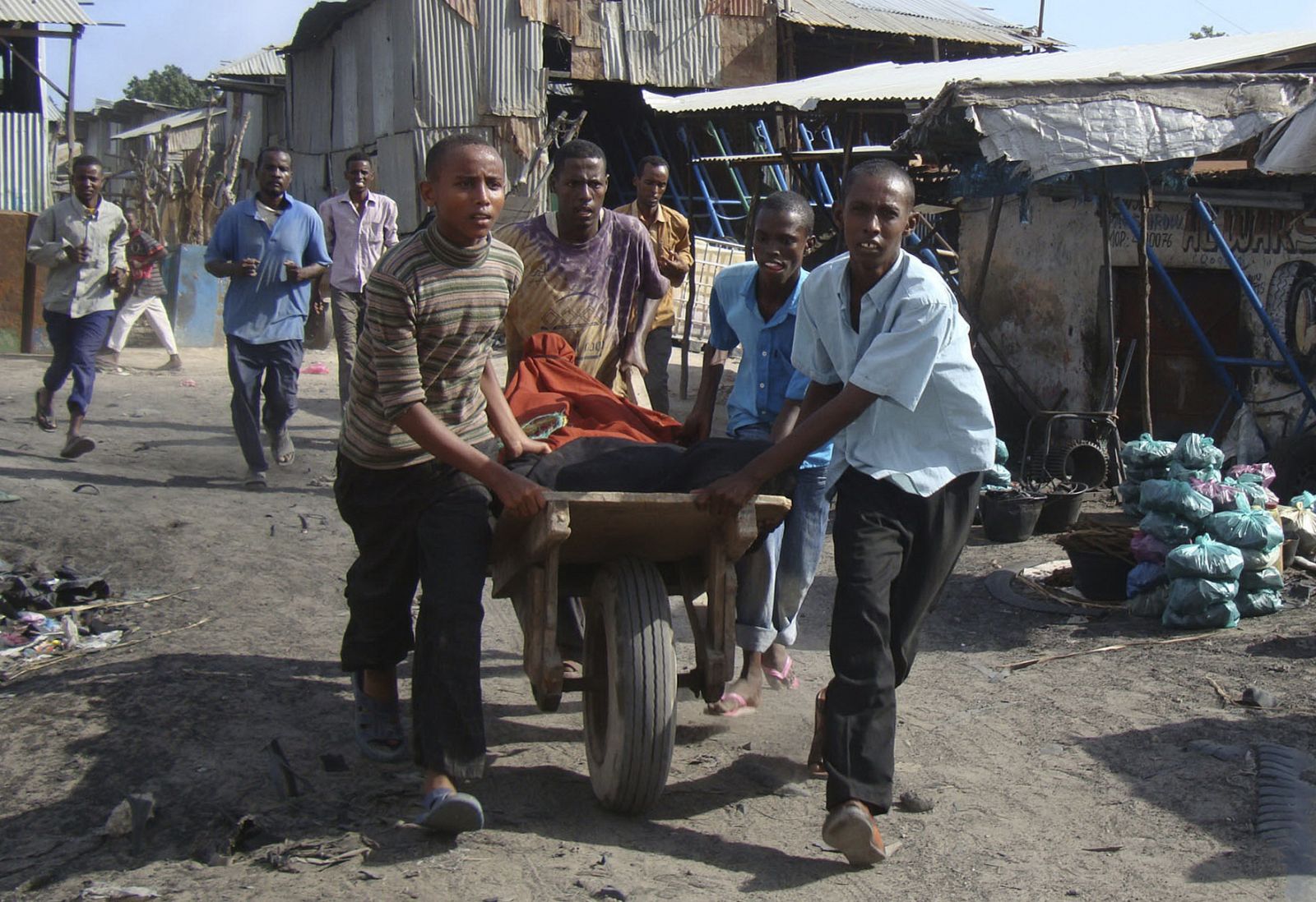 Somalis wheel a wounded man in a handcart after mortar shelling targeting Bakara market in the capital Mogadishu