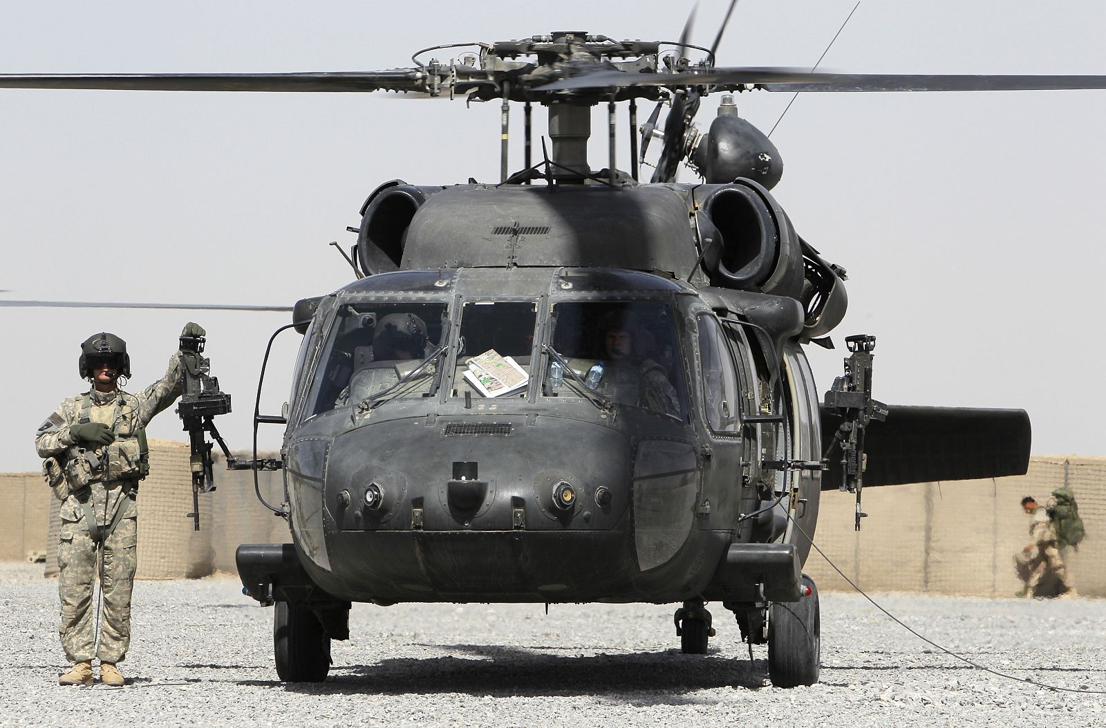 An airman stands next to a Black Hawk helicopter at a base near the village of Nakhonay