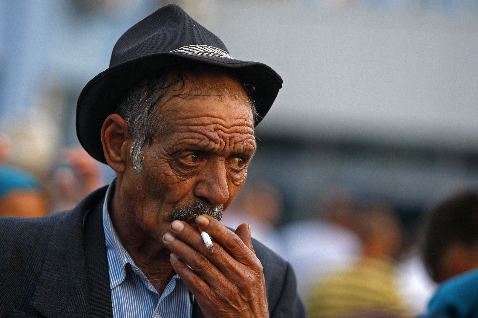 An elderly Roma man smokes after he arrives at Baneasa international airport in Bucharest from Marseille