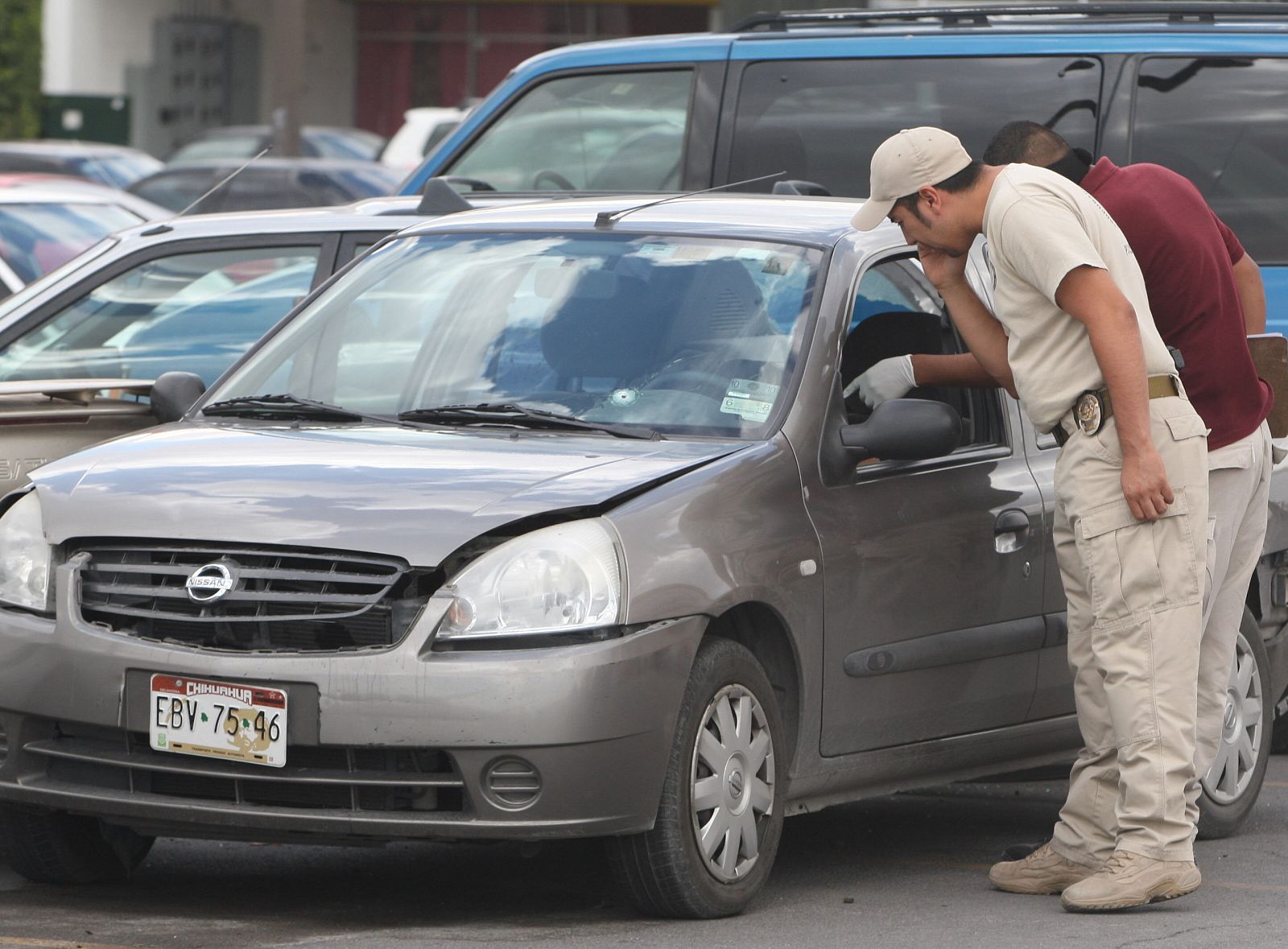 Peritos forenses recaban información en torno al vehículo en el que fue asesinado un fotógrafo mexicano en Ciudad Juárez.