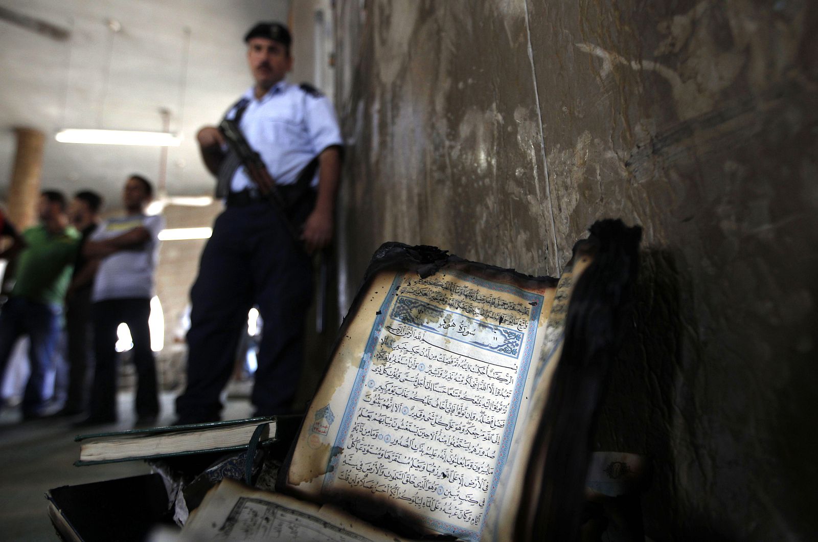 A partially burnt Koran is laid against the wall of a mosque that was vandalised in the West Bank village of Beit Fajjar