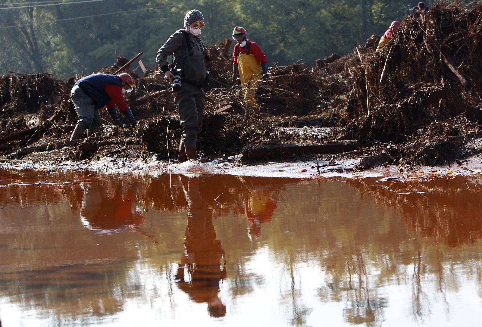 Reuters photographer Bernadett Szabo walks amid red toxic sludge in the flooded village of Devecser