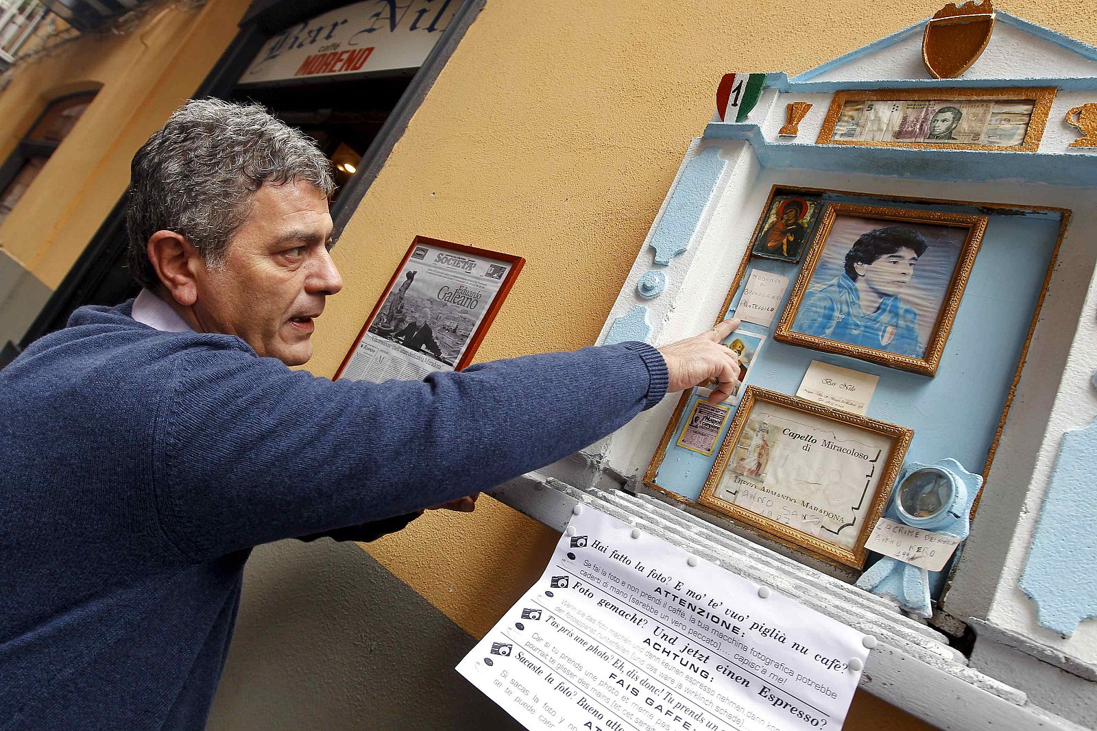 Nilo bar owner Carmine Alcide points to a small altar containing hair believed to belong to former Argentina international and Napoli soccer player Diego Armando Maradona in Naples