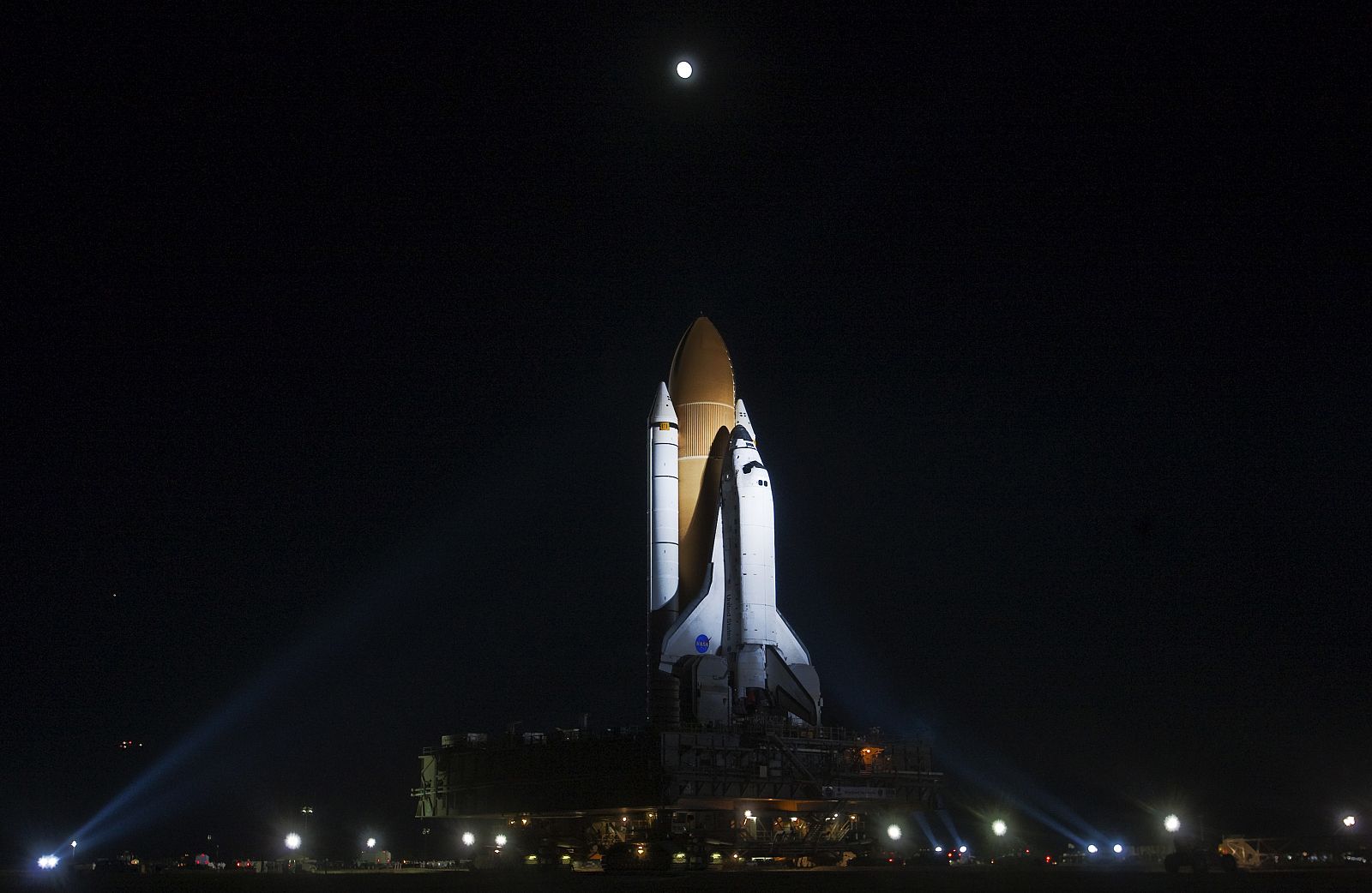 The space shuttle Discovery leaves the vehicle assembly building on the trip to launch pad 39A as the moon rises over Kennedy Space Center in Cape Canaveral
