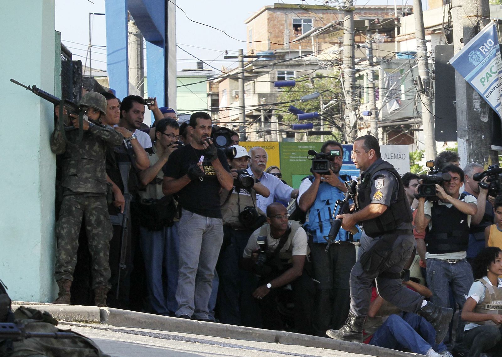 Army soldiers, police and journalists take their positions during an operation by the authorities at Alemao slum in Rio de Janeiro