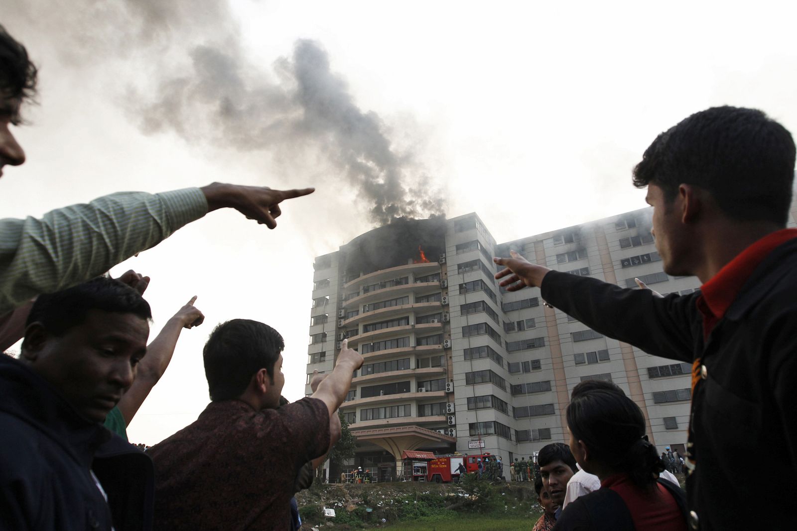 Workers point towards a man at the window of a burning garment factory in Ashulia