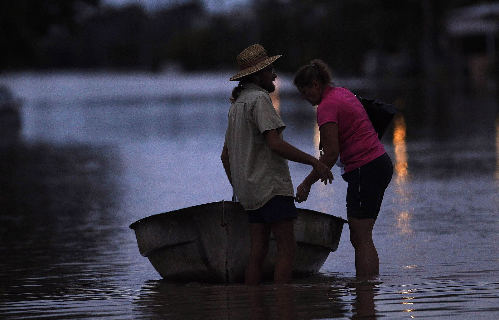 A couple prepares to board their boat along a street submerged in floodwaters at Depot Hill in Rockhampton