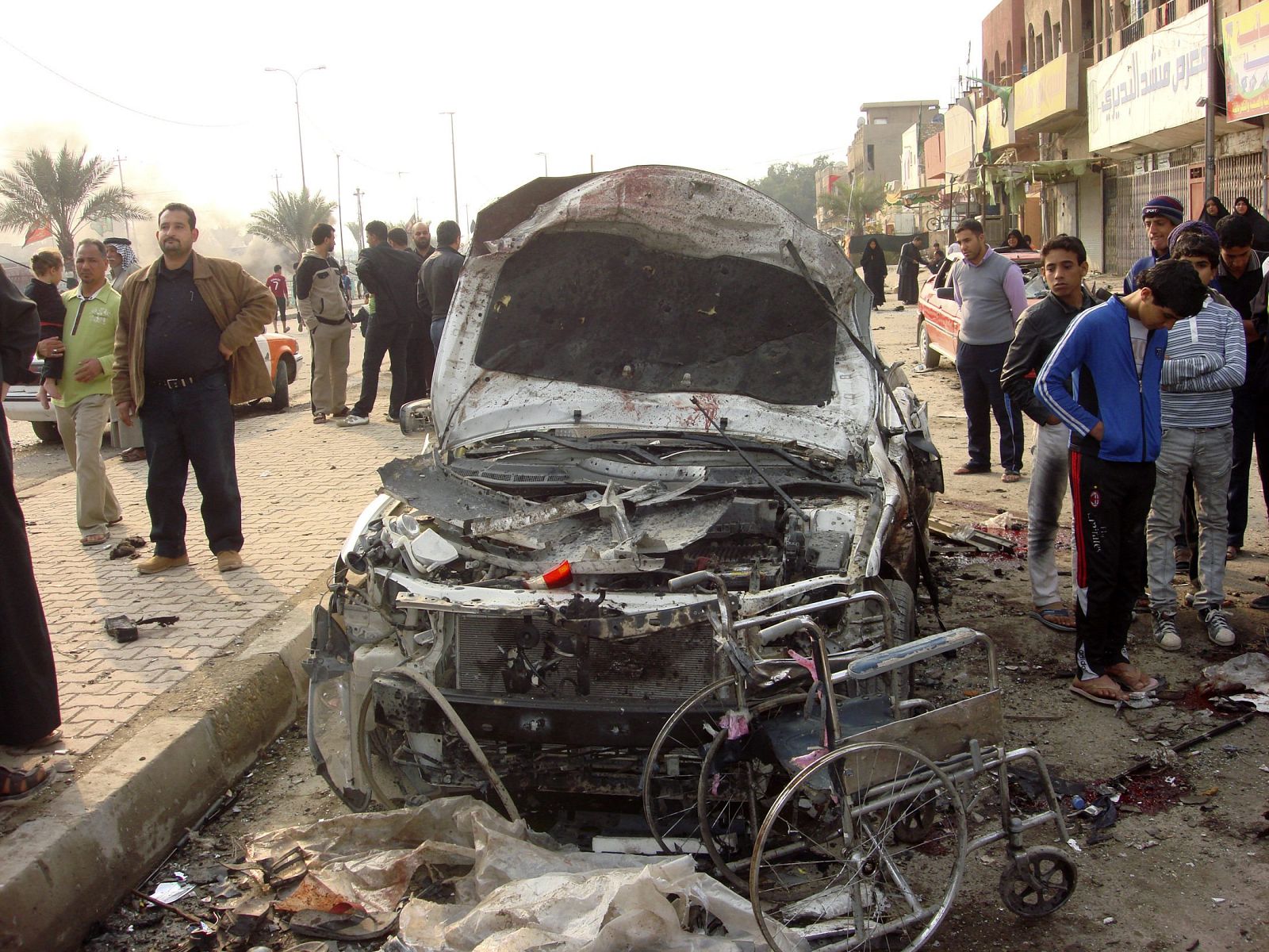 Residents gather at the site of a bomb attack in Baghdad's Shula district