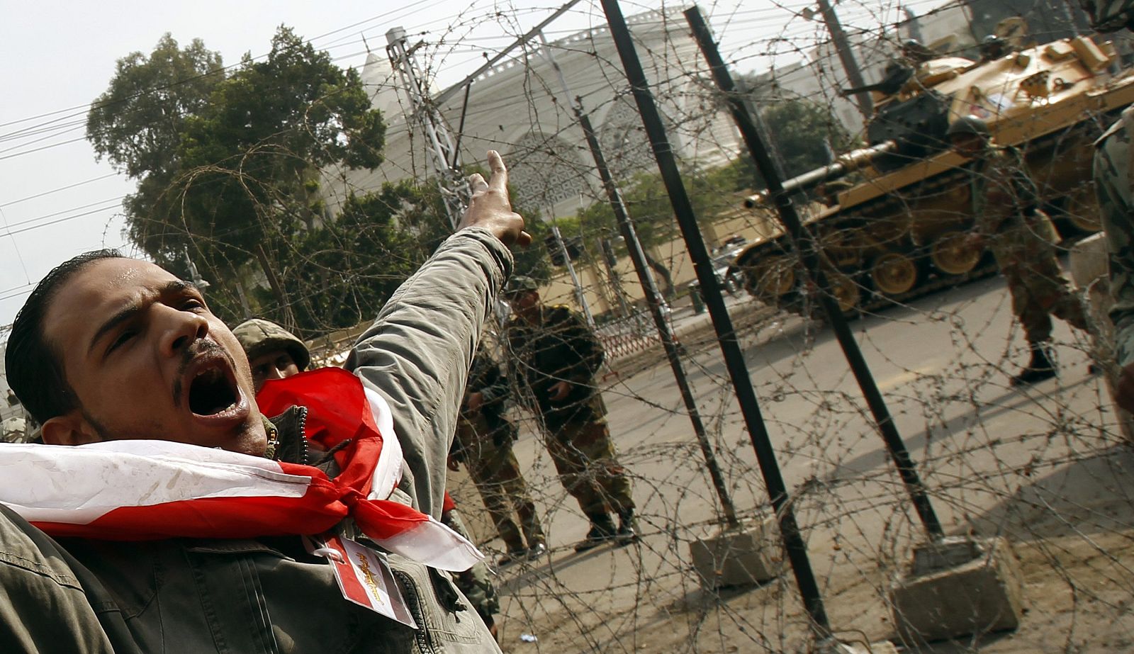 An opposition protester shouts in front of an army tank in front of the presidential palace in Cairo