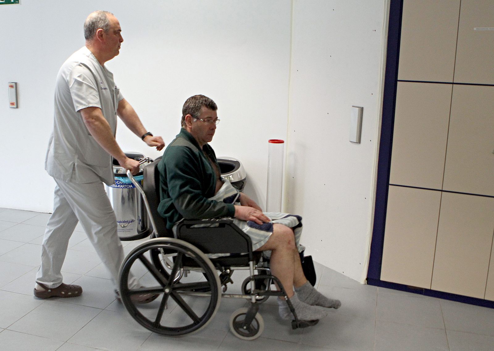 J.M.B. de 52 años, una de las dos personas que han sido rescatadas del naufragio de un pequeño barco en Zierbana (Vizcaya) es conducido en silla de ruedas en el hospital de Cruces.