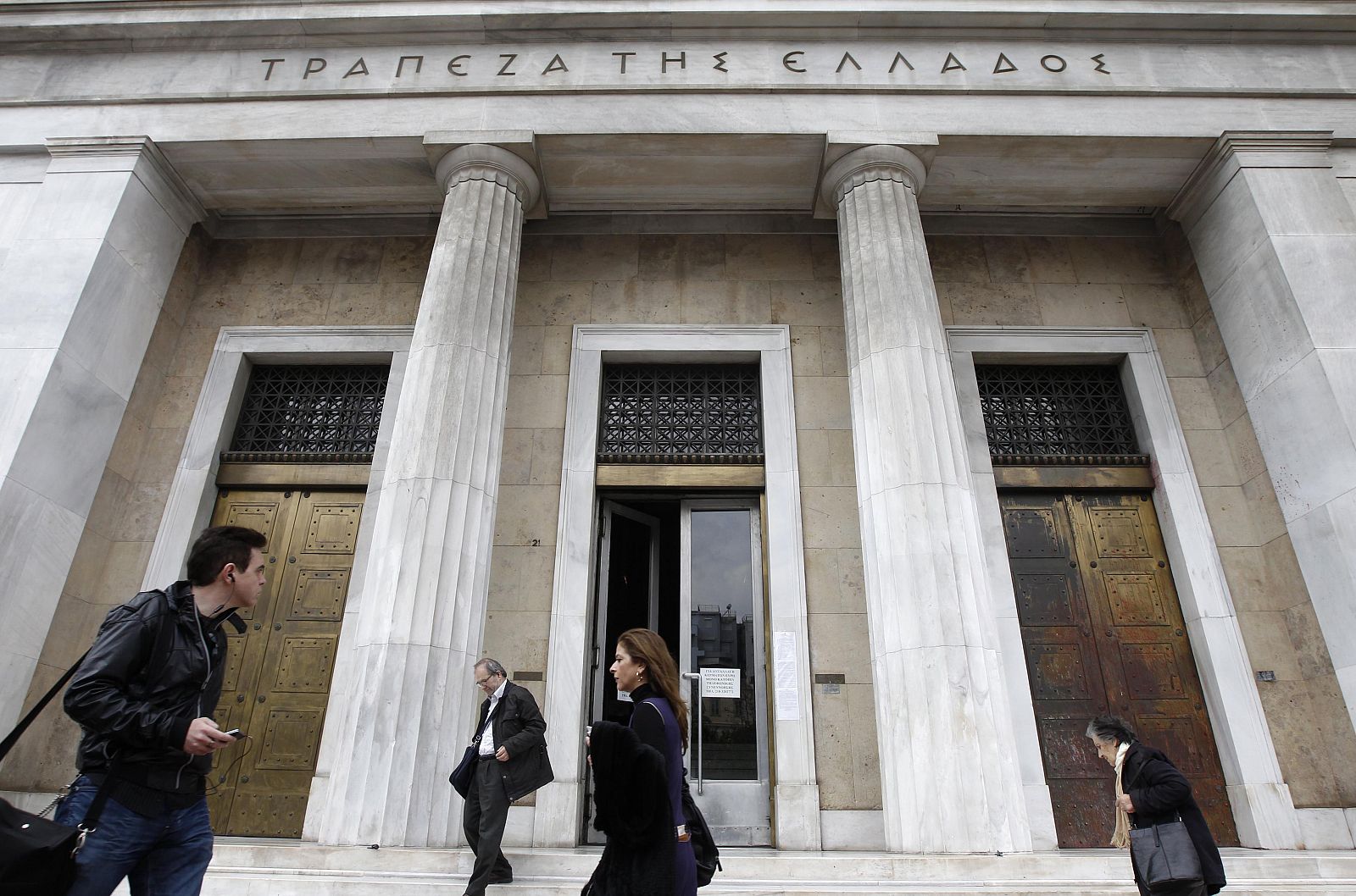 People walk past the Bank of Greece in central Athens