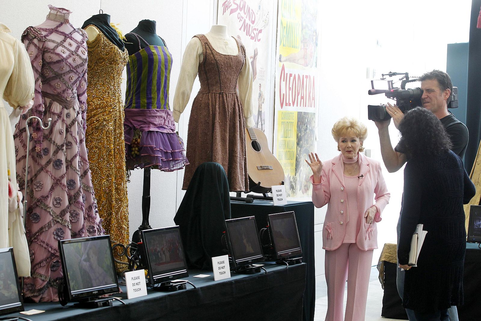 La actriz Debbie Reynolds posa con algunos vestidos de su colección subastada.