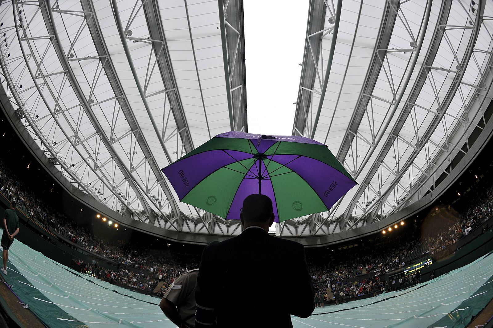 The umpire sits with an umbrella as the roof is closed over Centre Court during the match between Francesca Schiavone of Italy and Jelena Dokic of Australia at the Wimbledon tennis championships in London