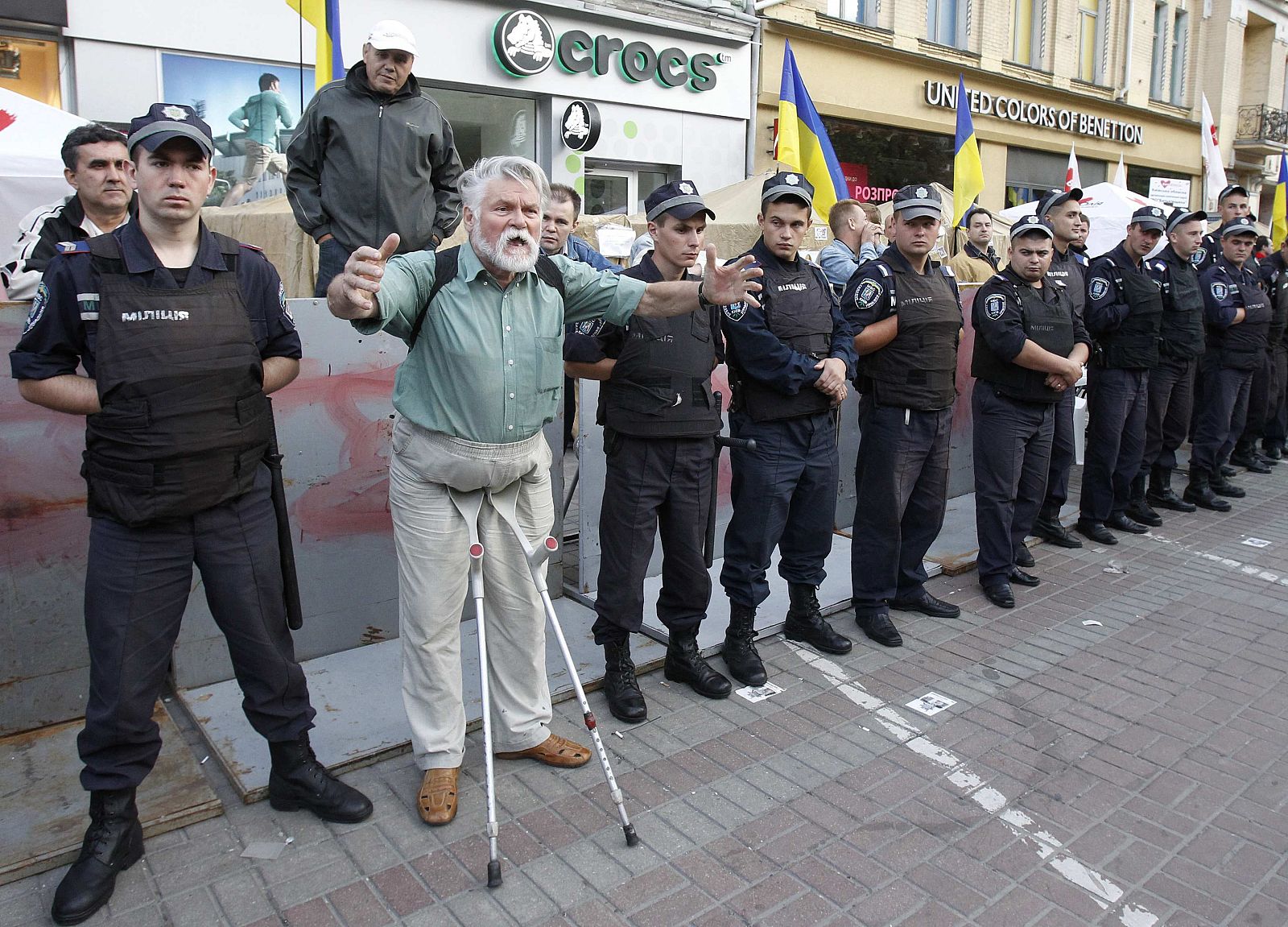 A supporter of former Ukrainian PM Tymoshenko reacts while Interior Ministry members stand guard near a tent camp outside the Pecherskiy District Court in Kiev