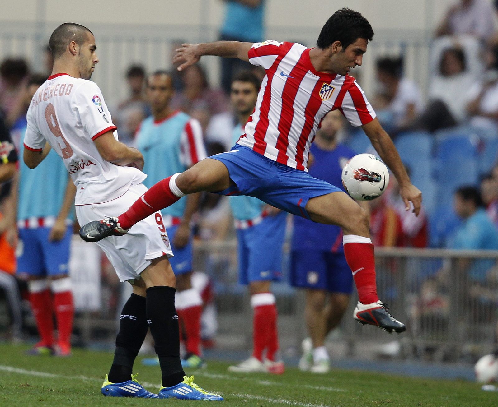 Atletico Madrid's Arda jumps for the ball in front of Sevilla's Negredo during their Spanish First Division soccer match at Santiago Calderon stadium in Madrid