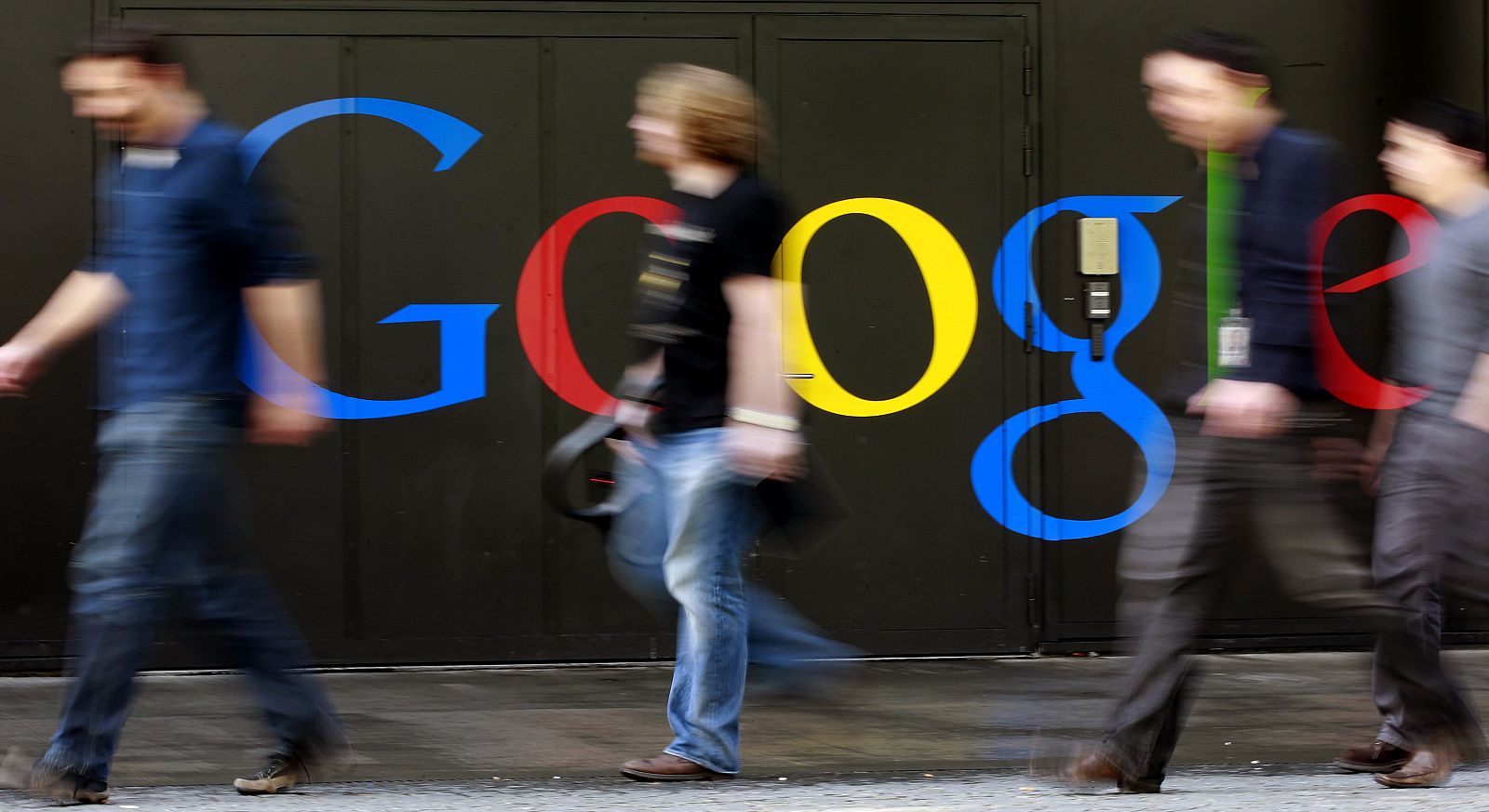 File photo of people walking past a logo next to the main entrance of the Google building in Zurich