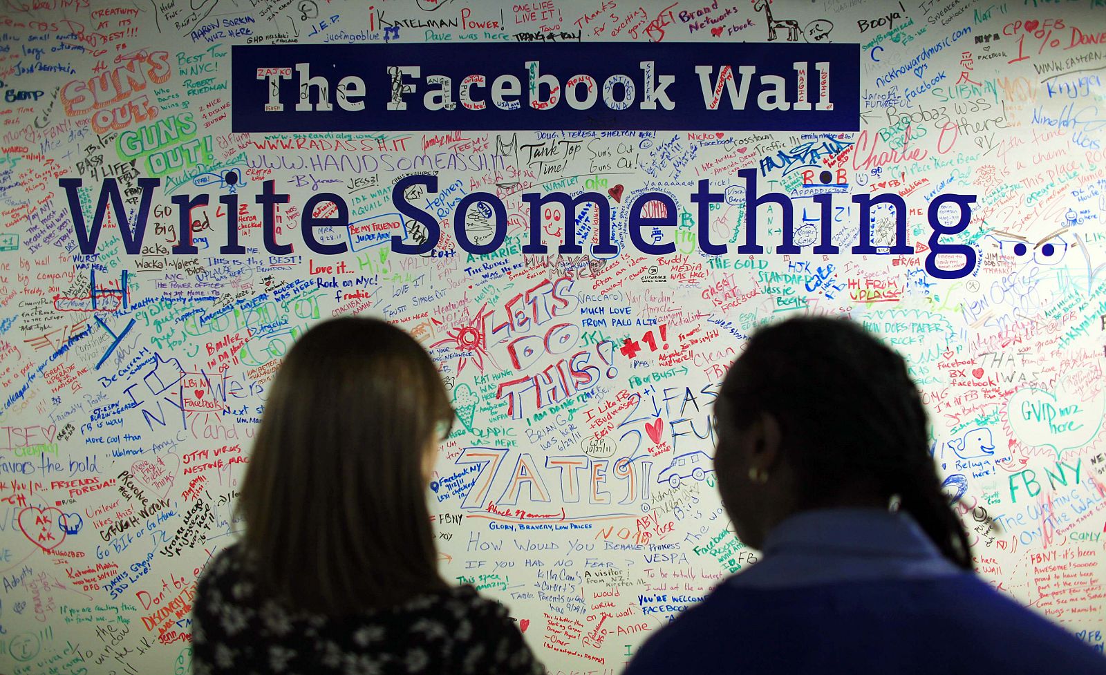 People look at the Facebook wall at their office in New York