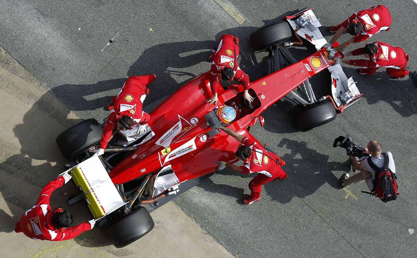 Mechanics push the car of Ferrari Formula One driver Fernando Alonso of Spain during a training session at Circuit de Catalunya racetrack
