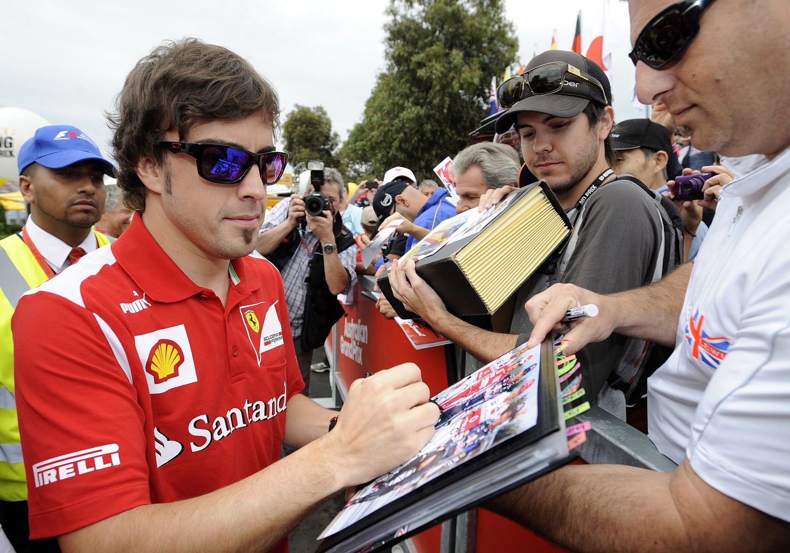 El piloto español de Fórmula 1 Fernando Alonso, de Ferrari, firma autógrafos antes del comienzo de la primera sesión de entrenamientos en el circuito de Albert Park en Melbourne (Australia).