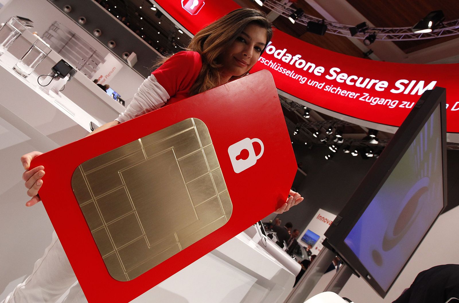 A staff member poses with a mock oversized Vodafone Secure SIM card at the Vodafone booth at the CeBit computer fair in Hanover