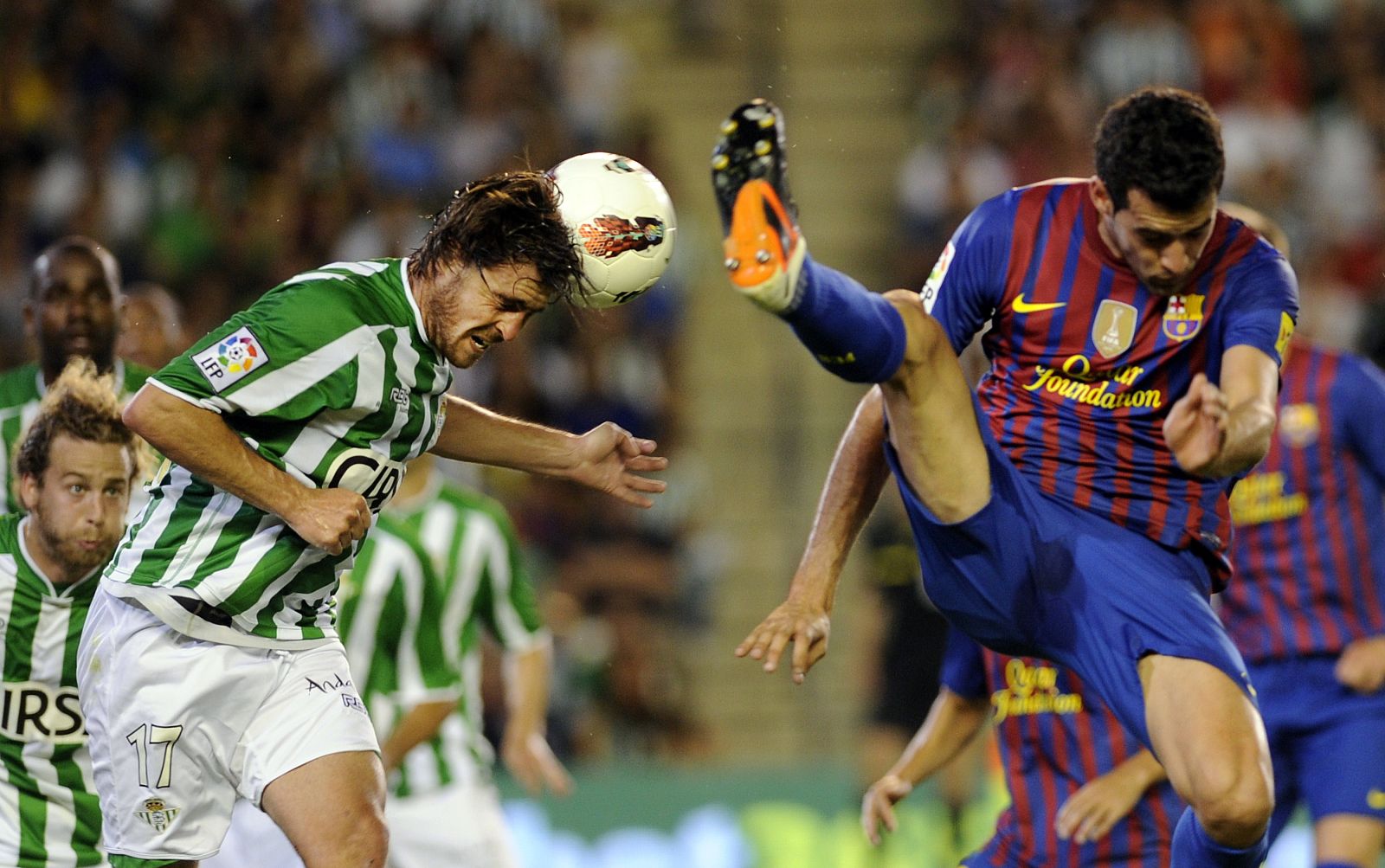 El barcelonista Sergio Busquets (d) pelea un balón con el jugador del Betis Javier Chica (i).
