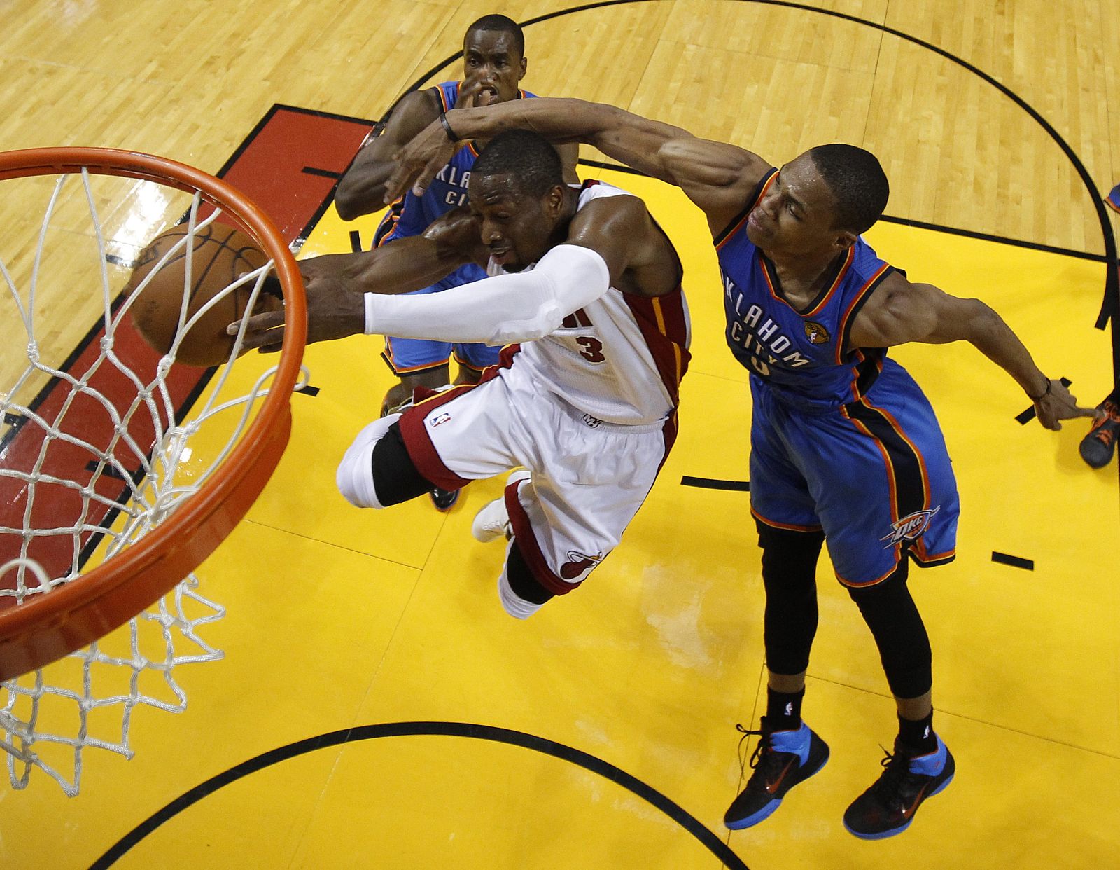 El jugador de Heat Dwyane Wade (c) se dirige a canasta ante la marca de Westbrook (d) y Serge Ibaka (i), de Thunder.