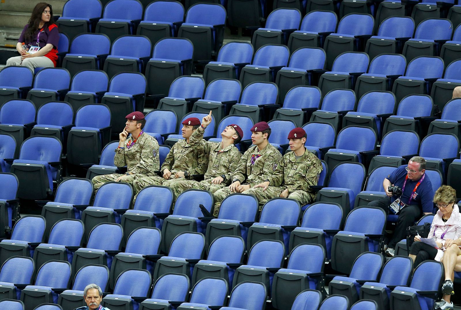 Soldiers sit in the empty seats held by the IOC as they watch the women's gymnastics qualification in the North Greenwich Arena during the London 2012 Olympic Games