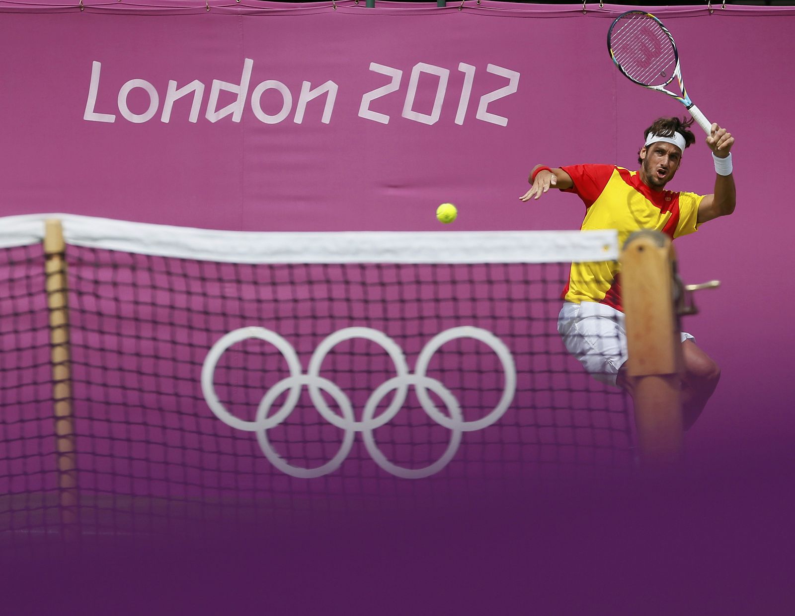 Spain's Lopez returns to Russia's Tursunov in their men's singles tennis match at the All England Lawn Tennis Club during the London 2012 Olympics Games