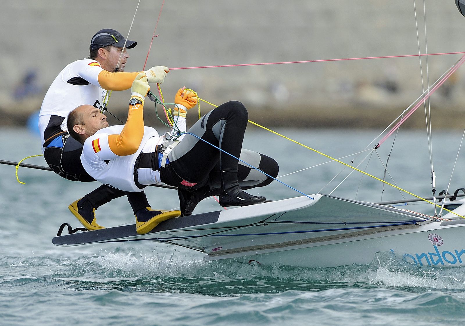 Los españoles Iker Martínez (i) y Xabier Fernández (2-i) drizan durante las pruebas de la clase 49er de los Juegos Olímpicos de Londres 2012