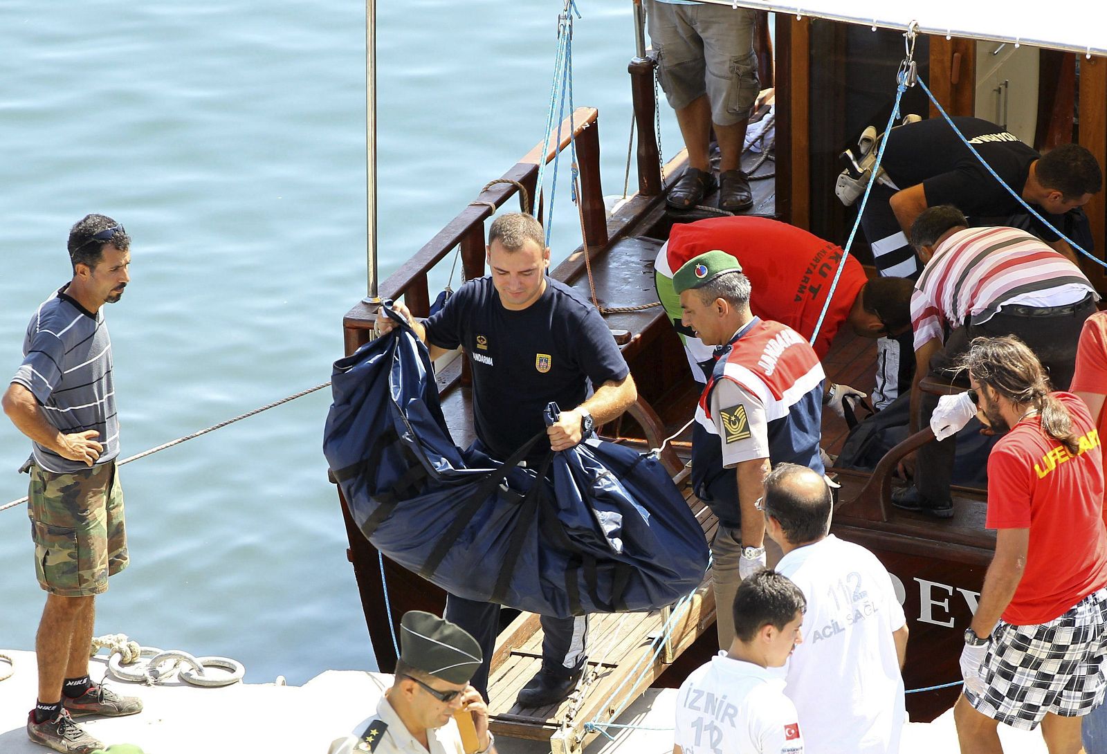 Miembros de la guardia costera turca cargan los cuerpos de las víctimas del naufragio en la costa del distrito de Menderes, en Esmirna