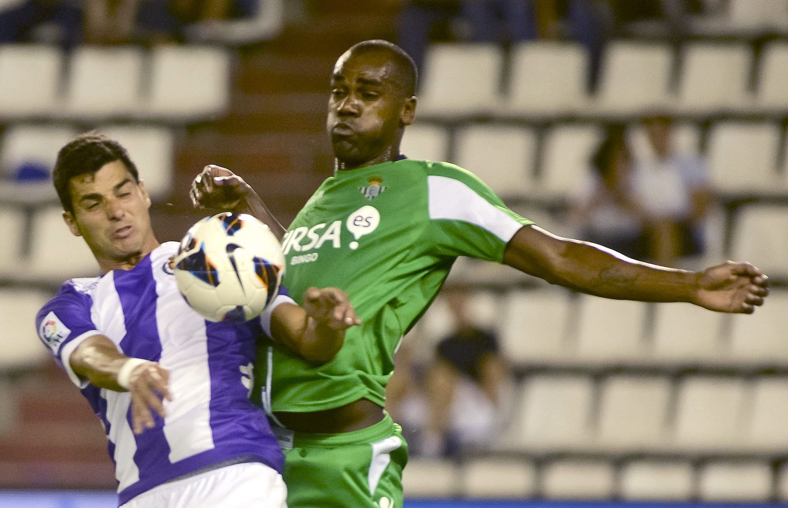 Paulao (d)  del Betis y Javi Guerra del Valladolid disputan un balón con las gradas vacías de fondo