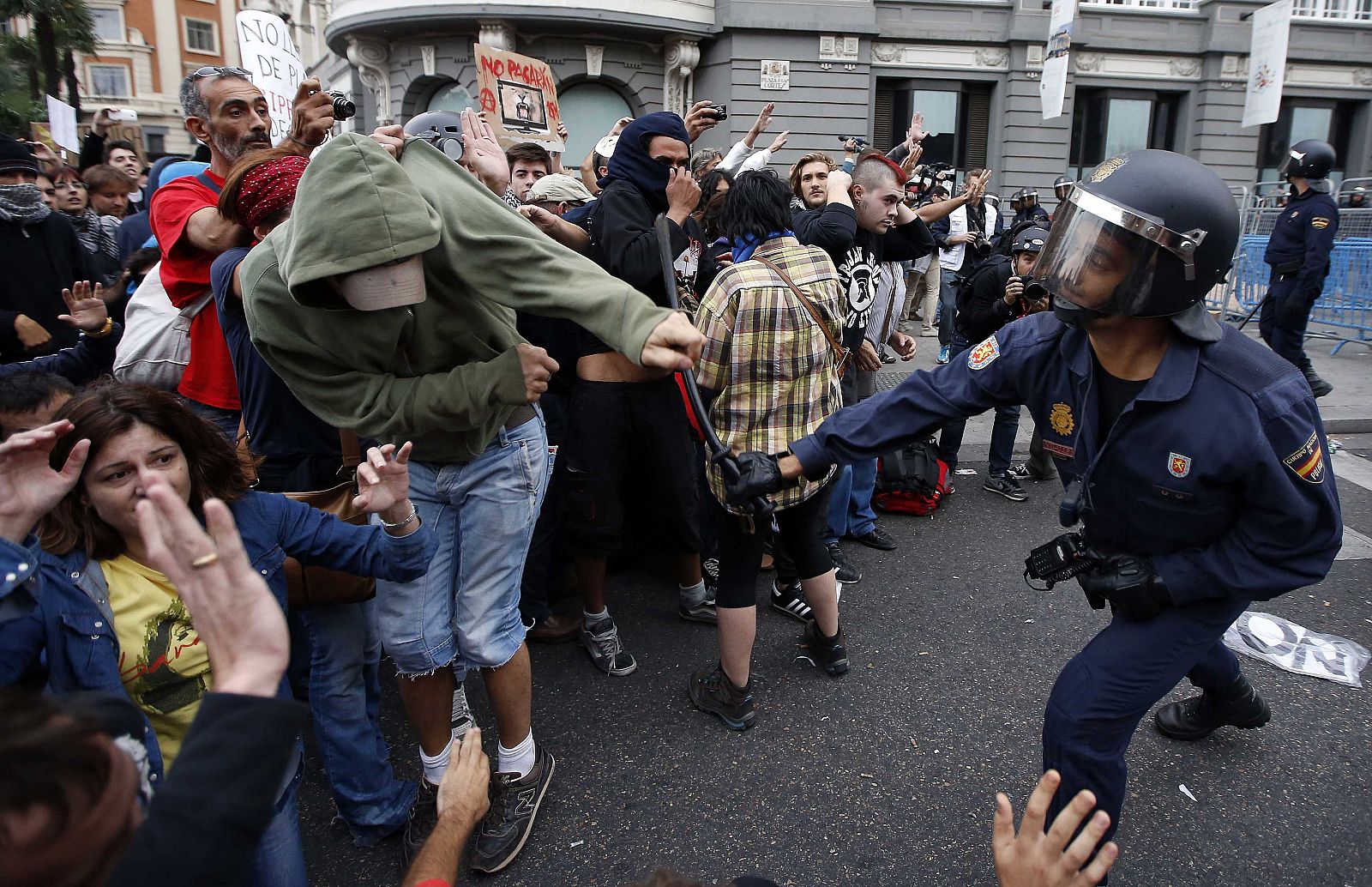 A policeman clubs a protester after police charged demonstrators outside the the Spanish parliament in Madrid