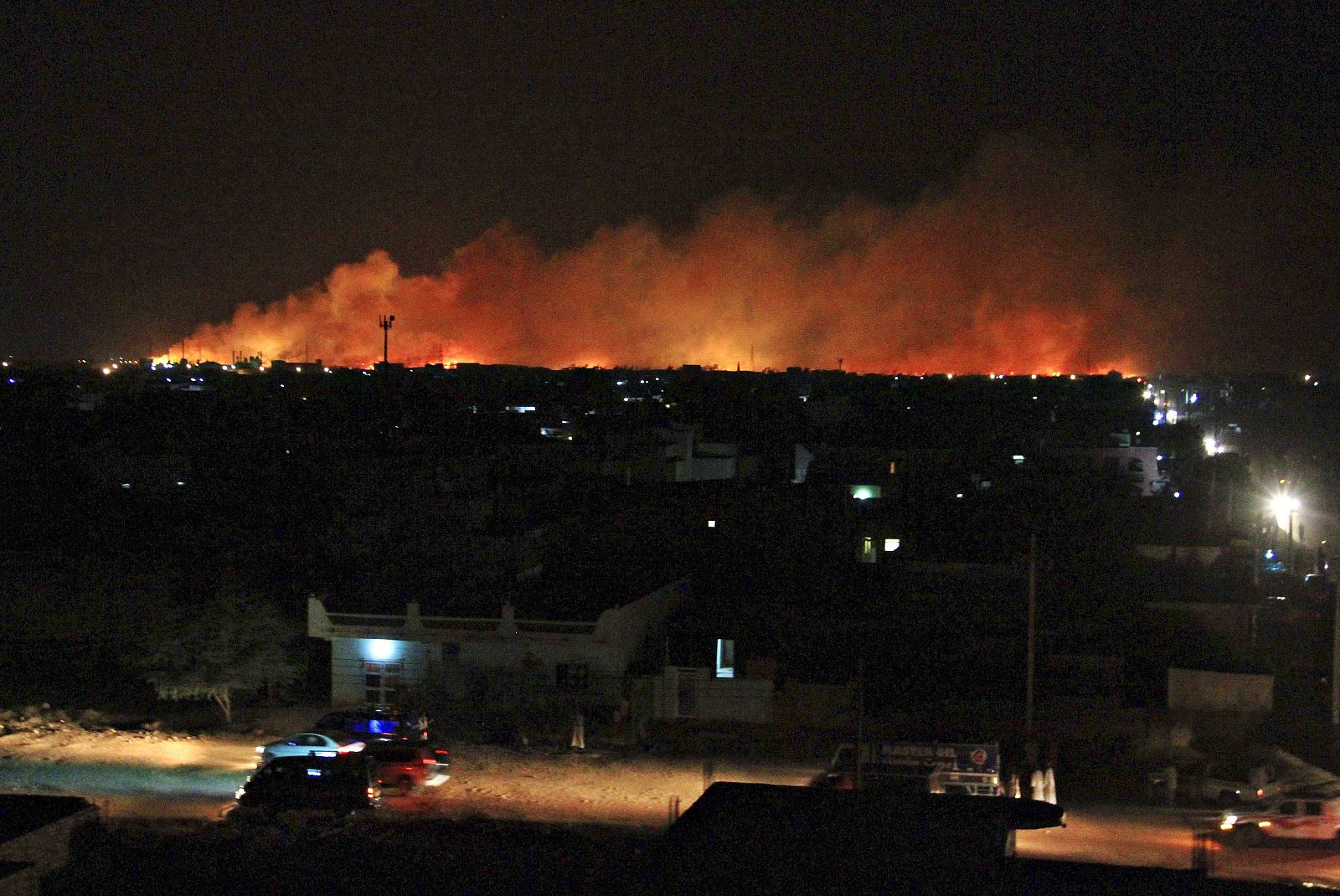 Onlookers gather to looks at a huge fire that engulf the Yarmouk ammunition factory in Khartoum