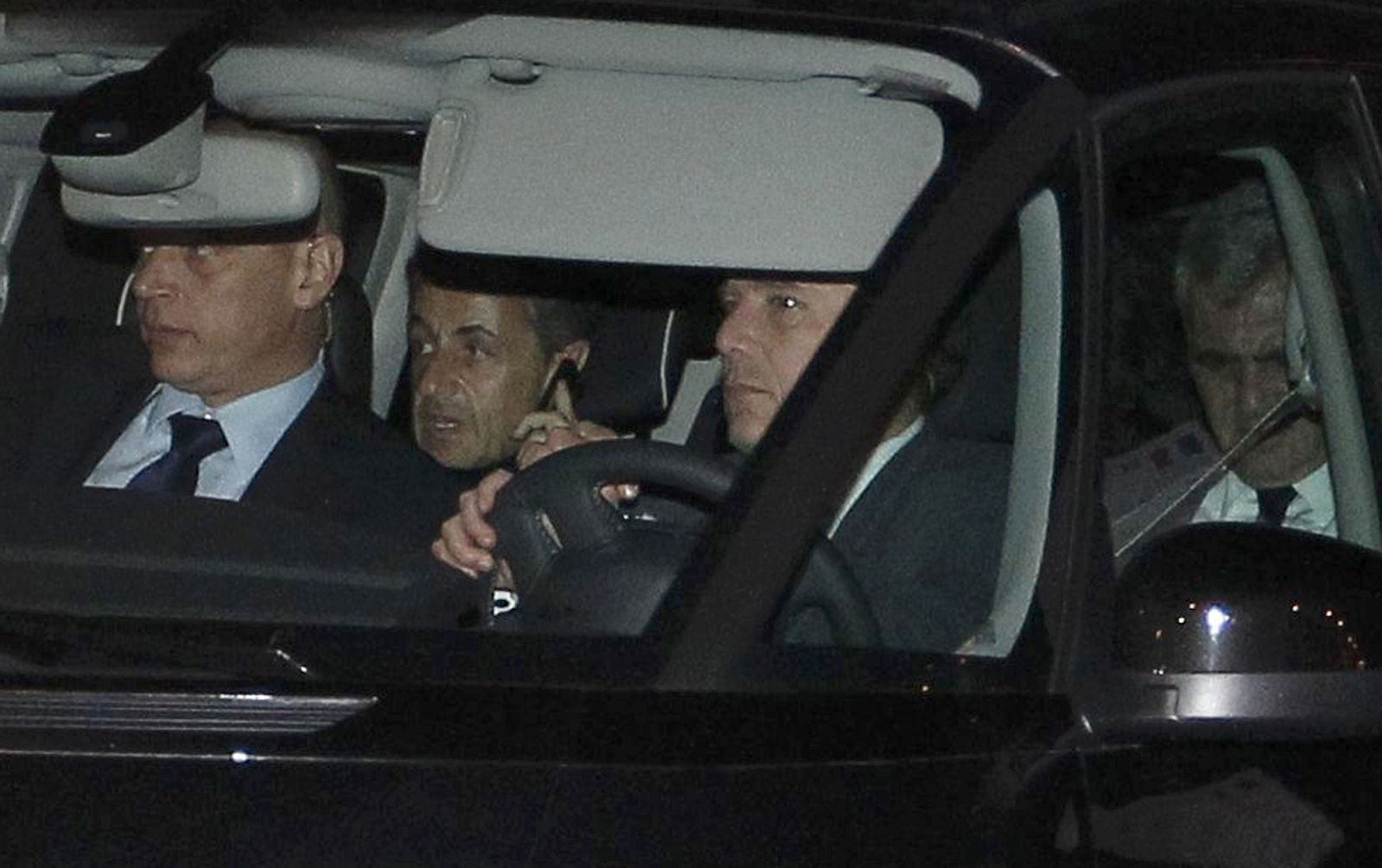 Former French President Sarkozy speaks on the phone as he sits near his lawyer Herzog as they leave the courthouse in Bordeaux