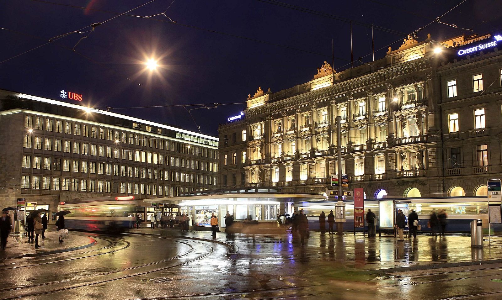 Trams drive past the offices of Swiss banks UBS and Credit Suisse at Paradeplatz square in Zurich