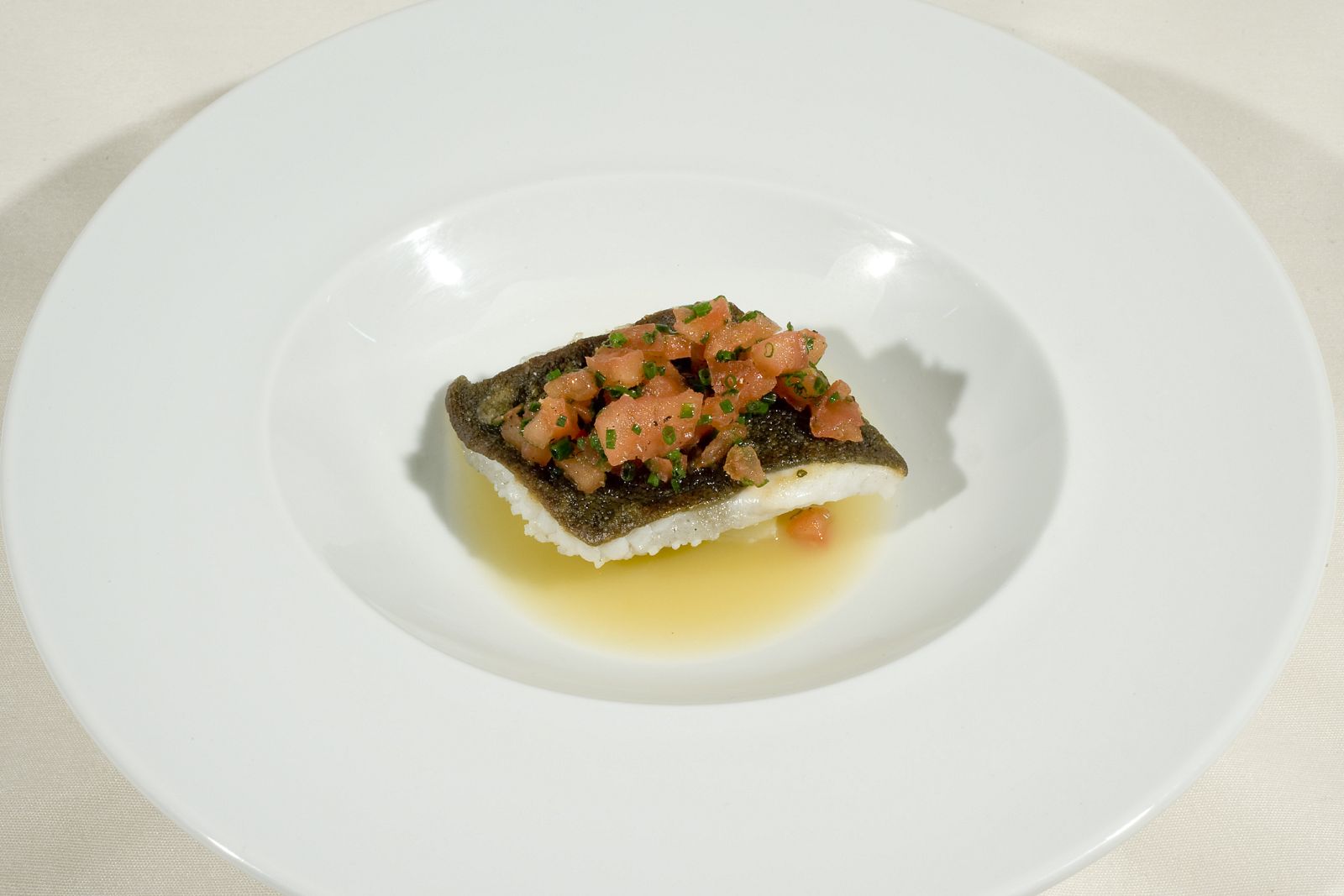 Rodaballo con tartar de tomate, patata confitada y jugo de almejas