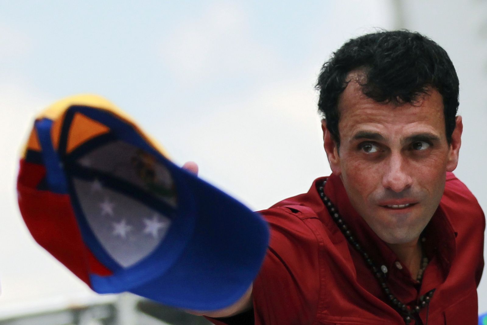 Venezuela's presidential candidate Capriles throws his cap to supporters during a campaign rally in Caracas