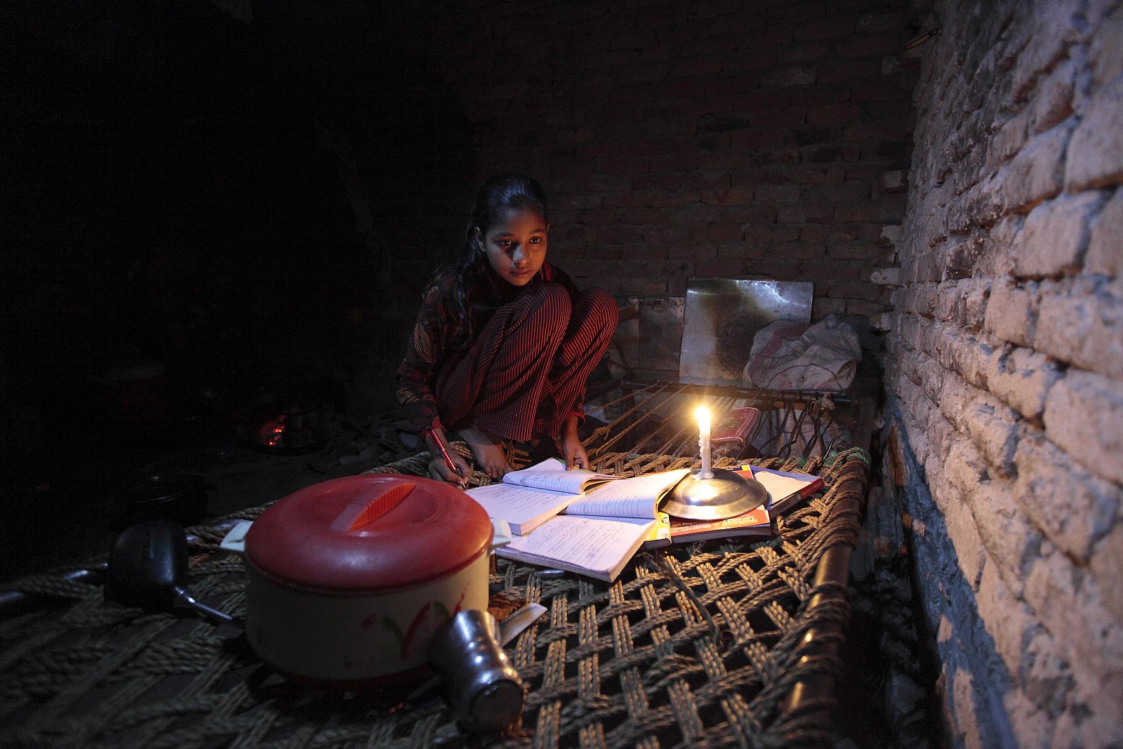 Norín, de 13 años, usa una vela para estudiar debido a un corte eléctrico en un barrio de chabolas de Islamabad