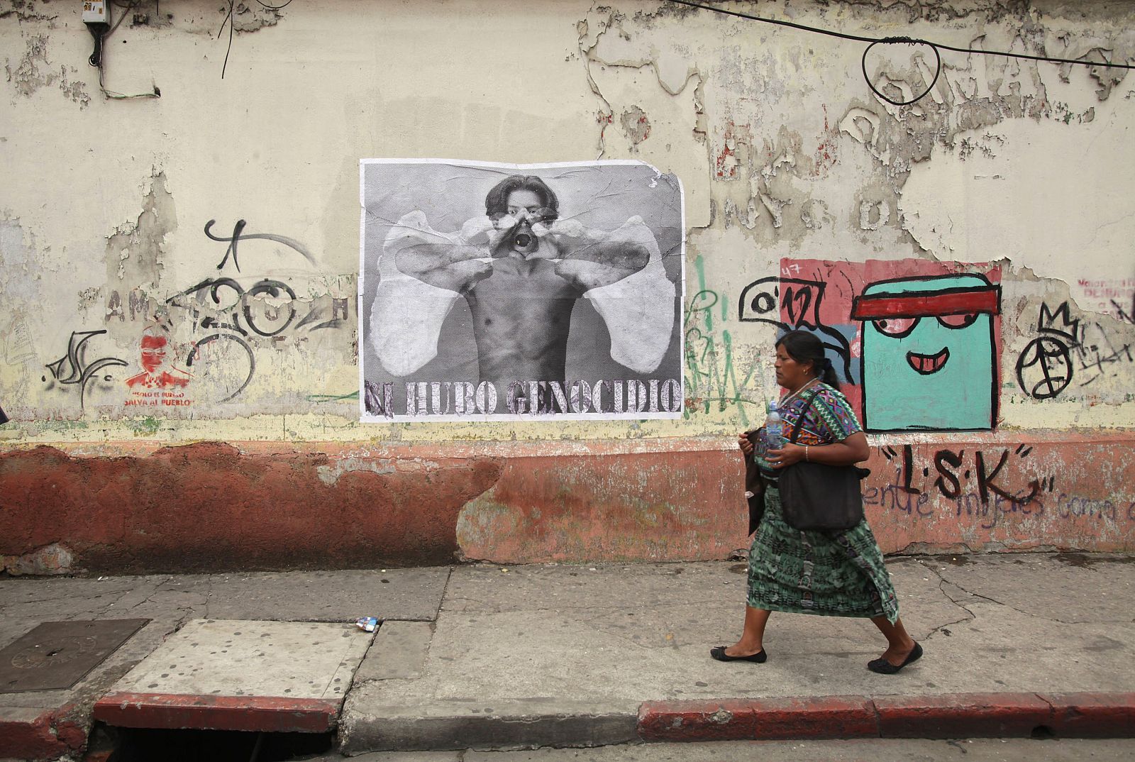 A indigenous woman walks past a poster on the streets during a demonstration against the overturn of the genocide conviction of former Guatemalan dictator Efrain Rios Montt in Guatemala City