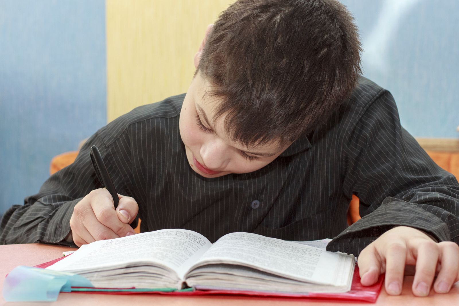 Niño haciendo los deberes con un libro de texto.