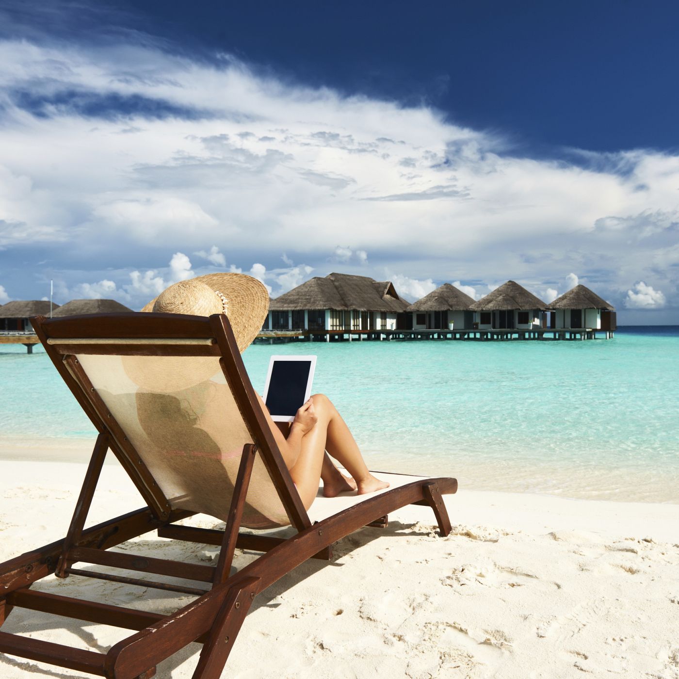 Una mujer con su tablet en la playa.