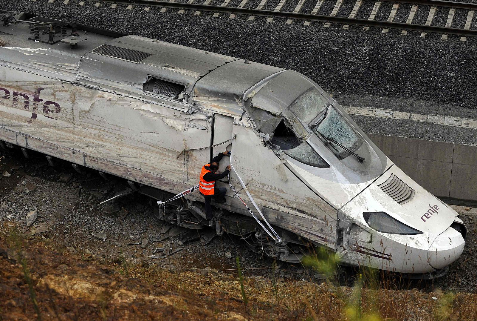 An official inspects the train engine amongst the wreckage of a train crash near Santiago de Compostela