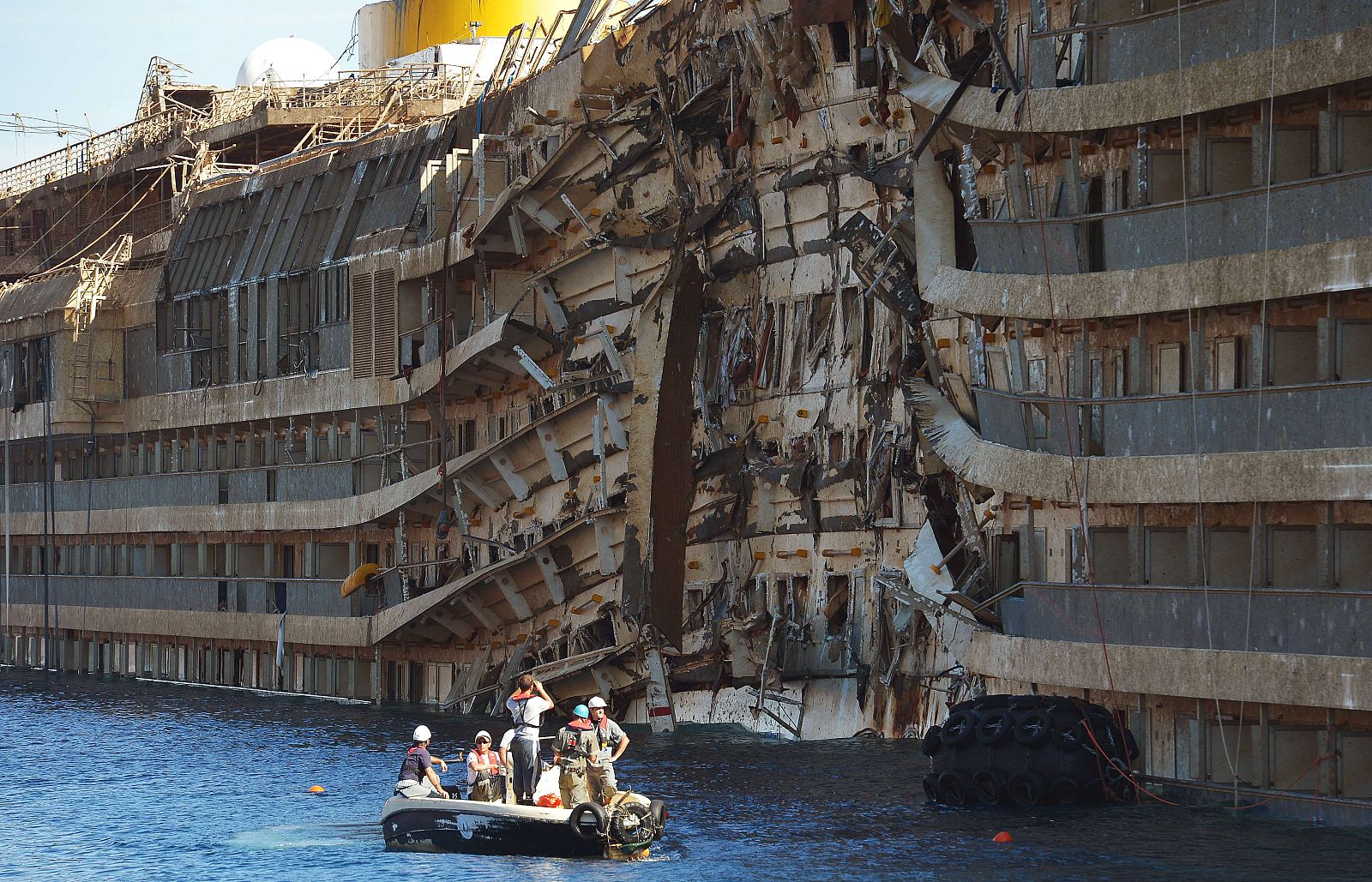 Miembros de los equipos de rescate inspeccionan el casco del 'Costa Concordia' frente a la isla de Giglio