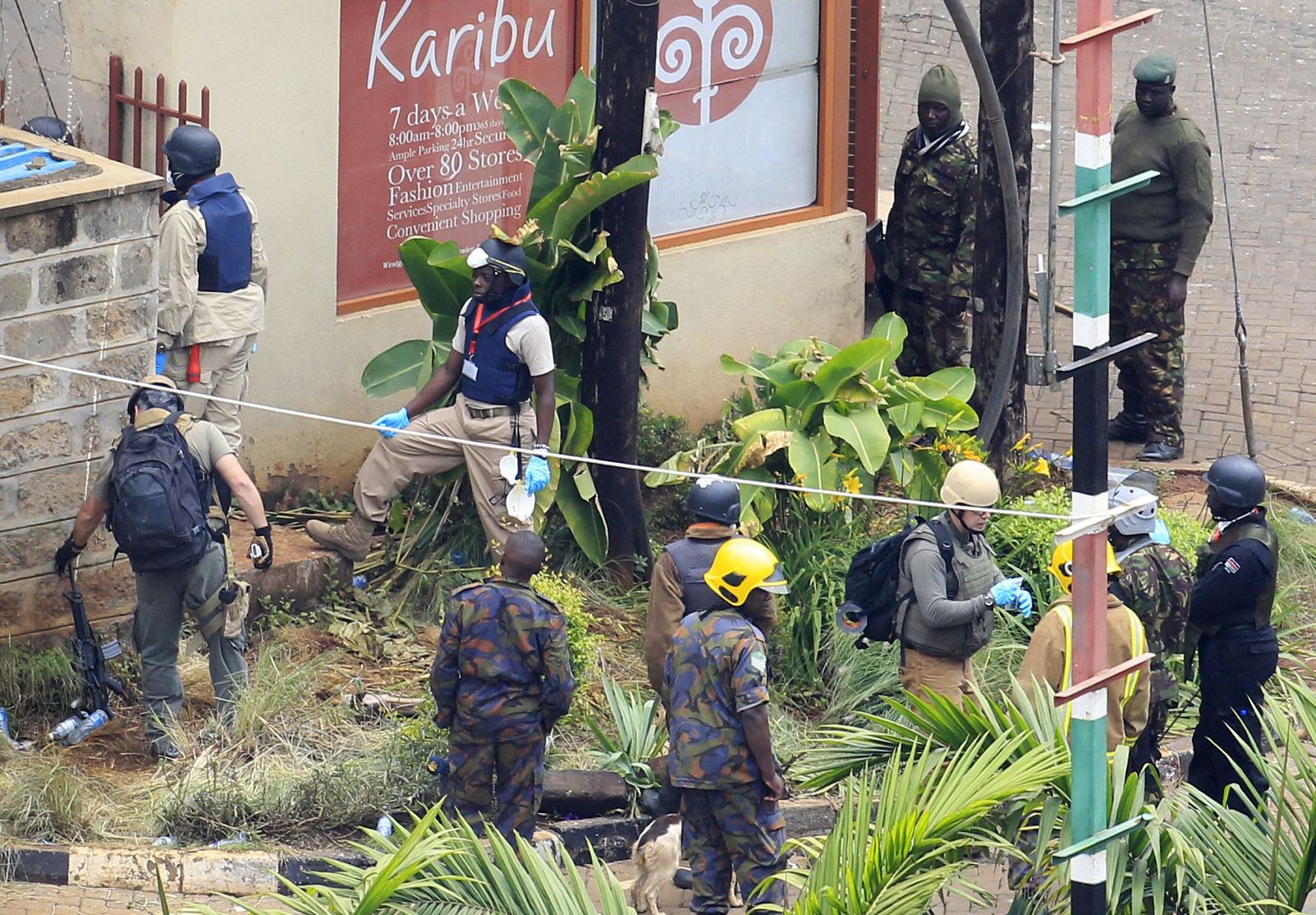 Foreign forensic experts, flanked by Kenyan military personnel, check the perimeter walls around Westgate shopping mall in Nairobi